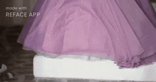 A Woman In A Purple Dress Is Standing On A White Block Of Ice . GIF