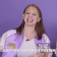 A Woman In A Purple Jacket Is Laughing And Holding A Glass . GIF