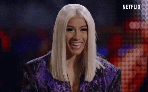 A Woman In A Purple Jacket Is Smiling In Front Of A Sign That Says Netflix GIF