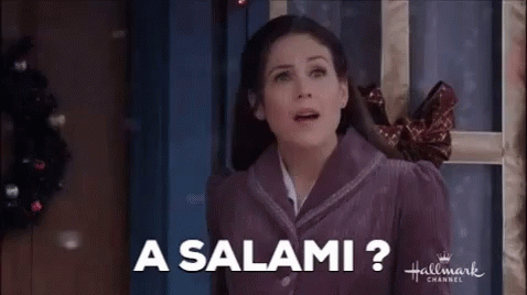 A Woman In A Purple Jacket Is Standing In Front Of A Door And Smiling . GIF