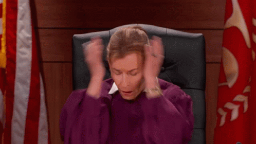A Woman In A Purple Robe Is Sitting In A Chair Holding Her Hands To Her Head . GIF