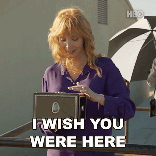 A Woman In A Purple Shirt Holds A Box And Says I Wish You Were Here GIF