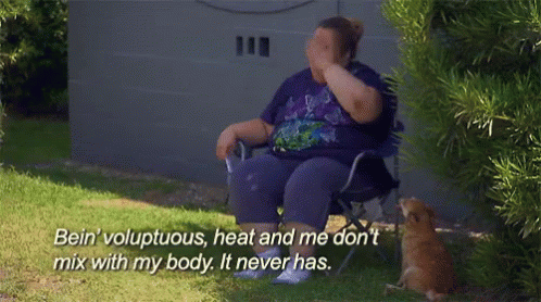 a woman in a purple shirt is sitting in a chair and covering her face with her hand while a cat watches
