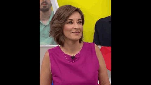 a woman in a purple shirt is sitting in front of a yellow wall .