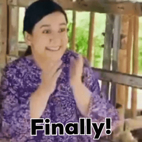 A Woman In A Purple Shirt Is Sitting On A Bench And Smiling . GIF