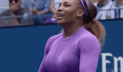 A Woman In A Purple Shirt Is Standing On A Tennis Court With Her Eyes Closed . GIF