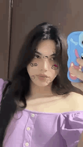 A Woman In A Purple Shirt Is Taking A Selfie With Her Phone . GIF