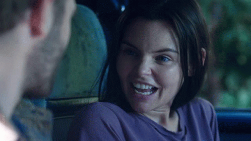 A Woman In A Purple Shirt Smiles While Looking At A Man GIF
