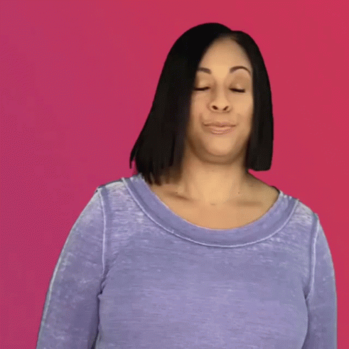 A Woman In A Purple Shirt With Her Hair Blowing In The Wind Against A Pink Background GIF