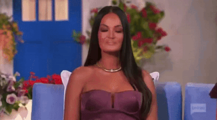 A Woman In A Purple Strapless Dress Is Sitting In A Chair . GIF