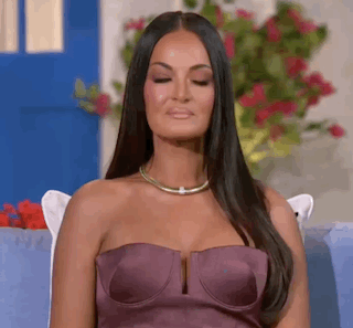 A Woman In A Purple Strapless Dress Is Sitting On A Couch . GIF