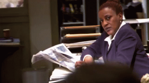 A Woman In A Purple Suit Is Reading A Newspaper . GIF