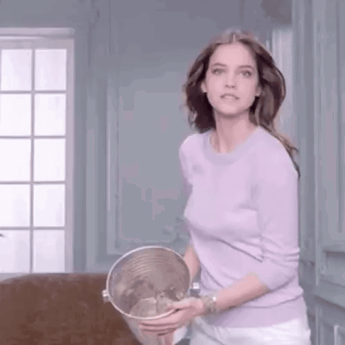 A Woman In A Purple Sweater Is Holding A Bucket Of Water In Her Hands . GIF
