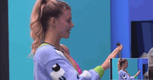 A Woman In A Purple Sweater Is Holding A Small Toy In Her Hand . GIF