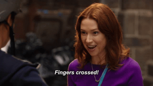 A Woman In A Purple Sweater Is Saying Fingers Crossed GIF