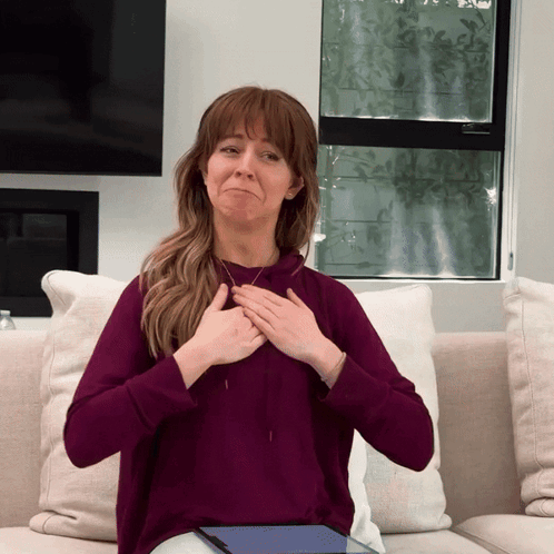 A Woman In A Purple Sweatshirt Is Sitting On A Couch GIF