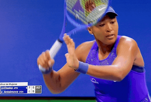 A Woman In A Purple Tank Top Holds A Tennis Racket GIF