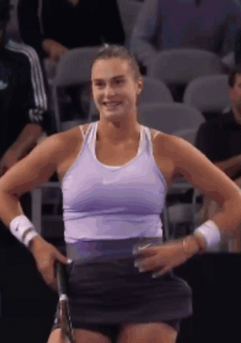 a woman in a purple tank top is holding a tennis racquet