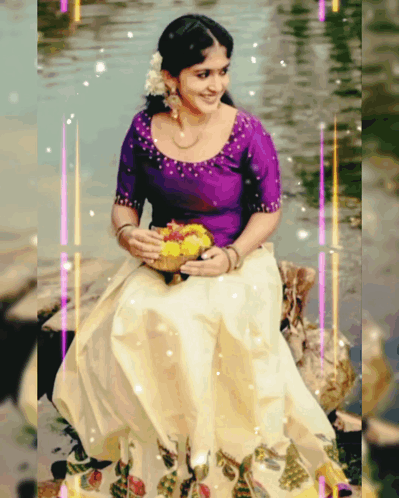 A Woman In A Purple Top And White Skirt Is Sitting On A Rock In The Water GIF