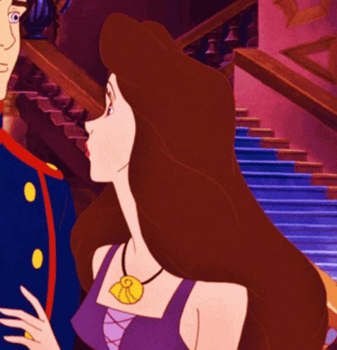A Woman In A Purple Top Has A Necklace With A Pendant That Says R On It GIF