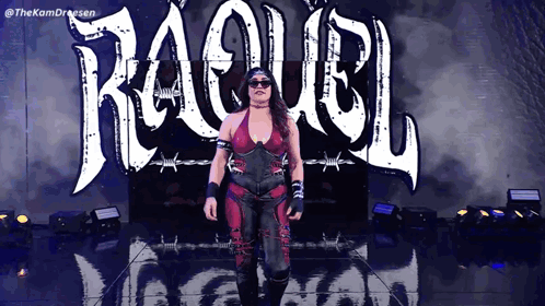 A Woman In A Red And Black Outfit Is Walking In Front Of A Sign That Says ' Raquel ' GIF