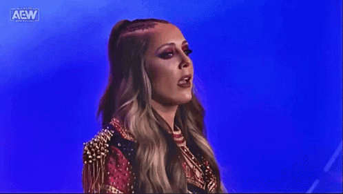 a woman in a red and gold outfit is standing in front of a blue background on a stage .