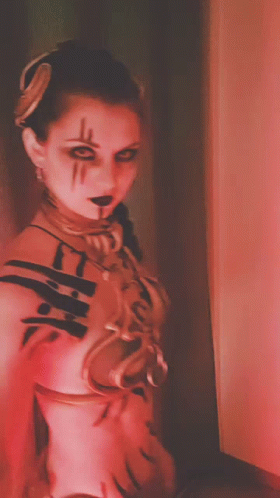 A Woman In A Red And White Costume With A Necklace Around Her Neck GIF