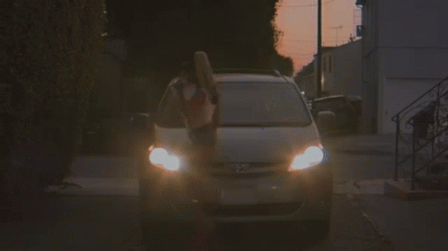 A Woman In A Red And White Crop Top Is Getting Out Of A Car . GIF