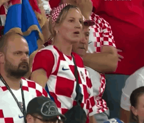 A Woman In A Red And White Nike Shirt Is Sitting In The Stands GIF