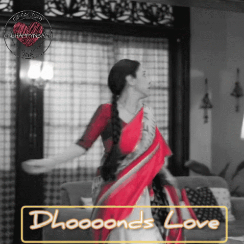 A Woman In A Red And White Saree Is Dancing In A Living Room GIF