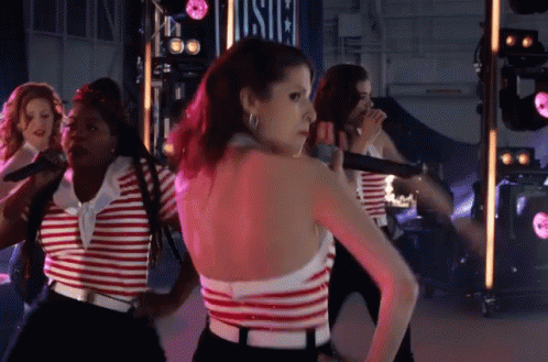 A Woman In A Red And White Striped Top Is Standing In Front Of A Sign That Says Usic GIF