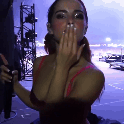 A Woman In A Red Bra Is Blowing A Kiss With A Purple Background GIF