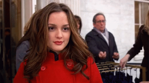 A Woman In A Red Coat Is Standing In Front Of A Display Of Clothes GIF