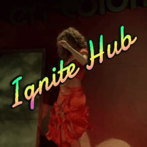 A Woman In A Red Crop Top Is Standing In Front Of A Neon Sign That Says Ignite Hub GIF