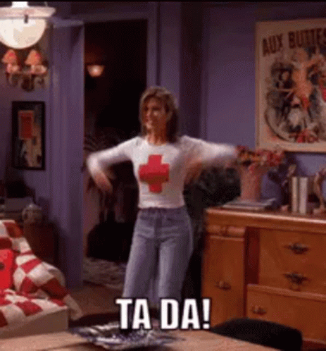 a woman in a red cross shirt is dancing in a living room with the words ta da on the bottom .