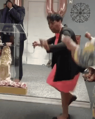 A Woman In A Red Dress And Black Jacket Is Dancing In Front Of A Mirror GIF