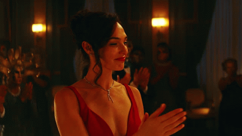 A Woman In A Red Dress And Necklace Is Clapping GIF