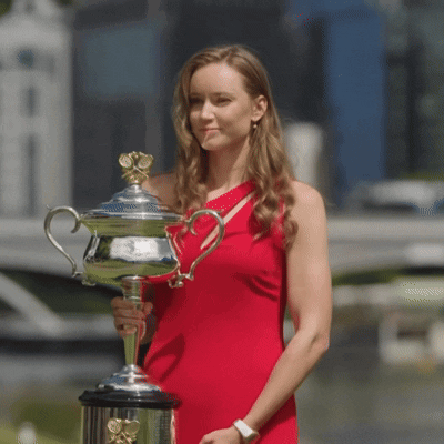 A Woman In A Red Dress Holding A Trophy GIF