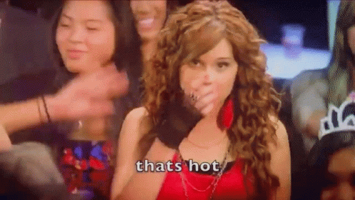 A Woman In A Red Dress Is Covering Her Mouth With Her Hand While A Crowd Of People Applaud . GIF