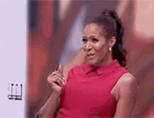 A Woman In A Red Dress Is Crying While Sitting In Front Of A Screen . GIF