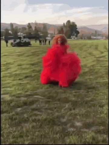A Woman In A Red Dress Is Dancing In A Field . GIF