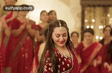 A Woman In A Red Dress Is Dancing In Front Of A Crowd Of People . GIF