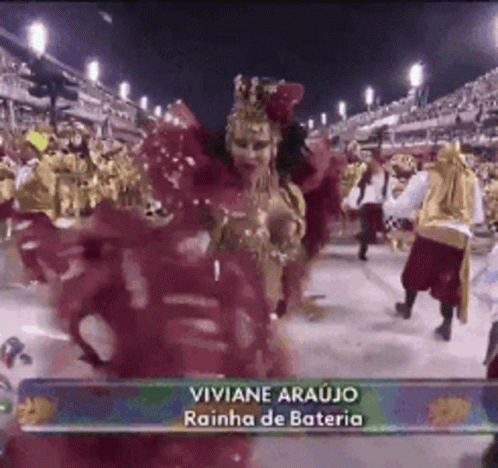 A Woman In A Red Dress Is Dancing In Front Of A Crowd With The Name Viviane Araujo On The Bottom Right GIF