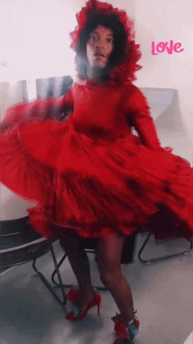 A Woman In A Red Dress Is Dancing In Front Of A Wall That Says Love GIF