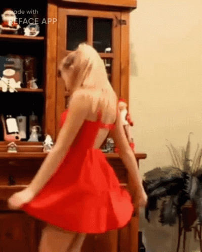 A Woman In A Red Dress Is Dancing In Front Of A Wooden Cabinet Made With The Face App GIF