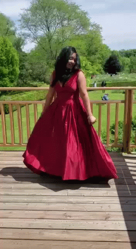 A Woman In A Red Dress Is Dancing On A Deck . GIF