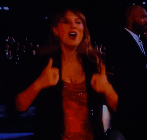 A Woman In A Red Dress Is Dancing On A Stage In Front Of A Crowd GIF