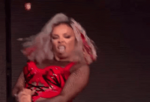 A Woman In A Red Dress Is Dancing On A Stage In Front Of A Purple Background . GIF