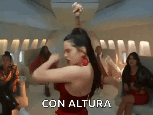 A Woman In A Red Dress Is Dancing On An Airplane With The Words Con Altura Written On The Bottom . GIF