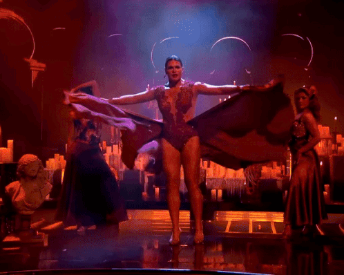 A Woman In A Red Dress Is Dancing On Stage GIF